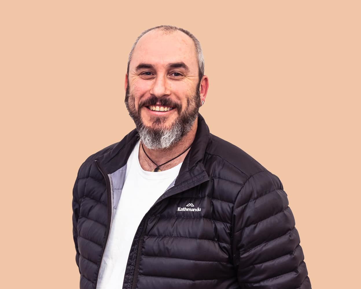 A man in a black jacket smiles at camera