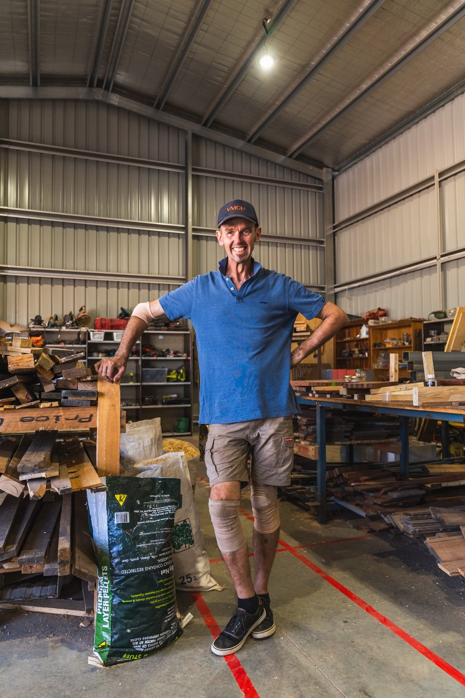 Man standing in shed wearing a blue shirt and blue hat