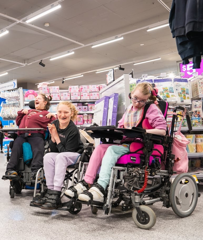 A group of friends using wheelchairs enjoy spending time together while out shopping in the community.