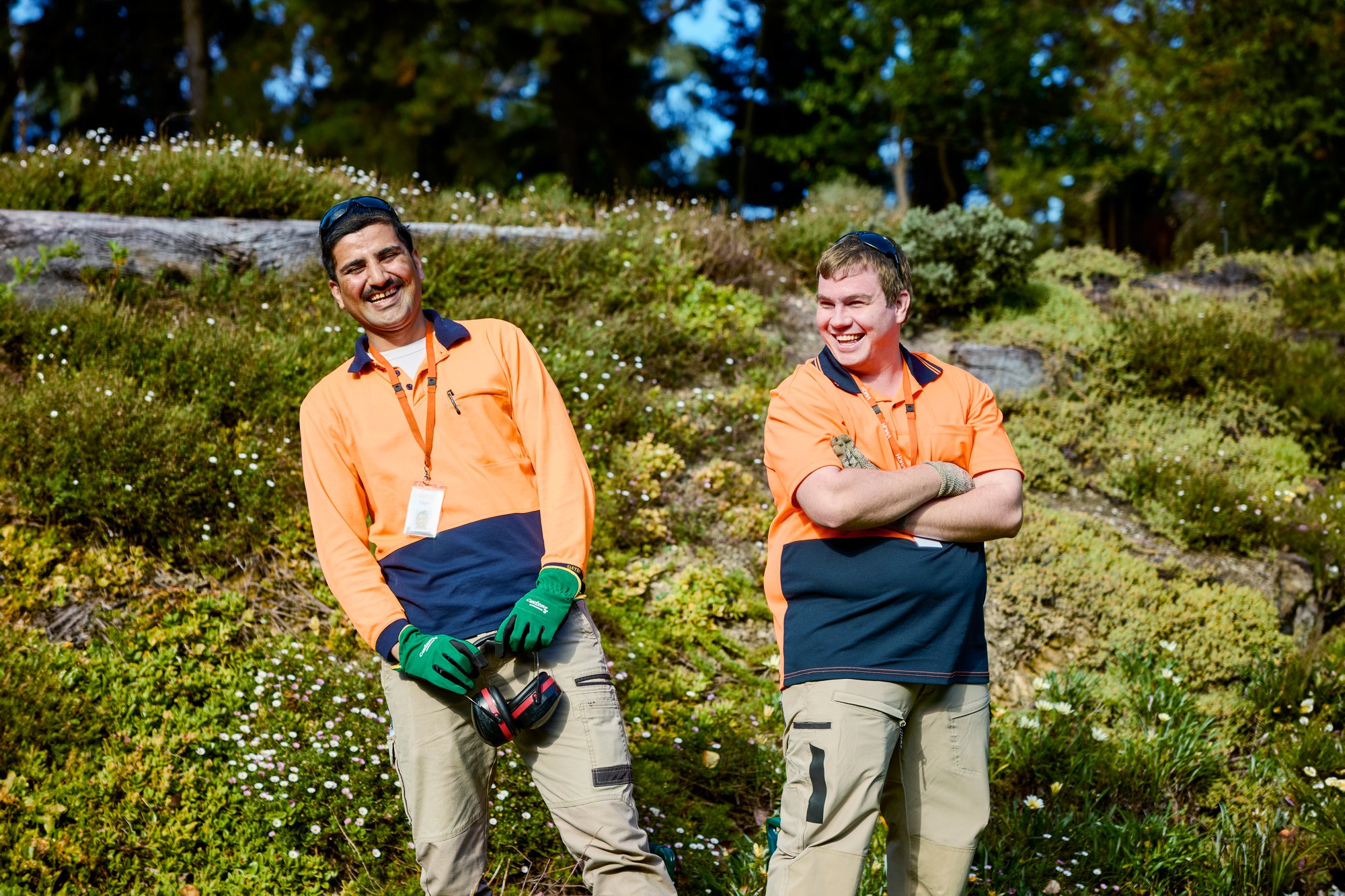 two men wearing high vis stand in a garden