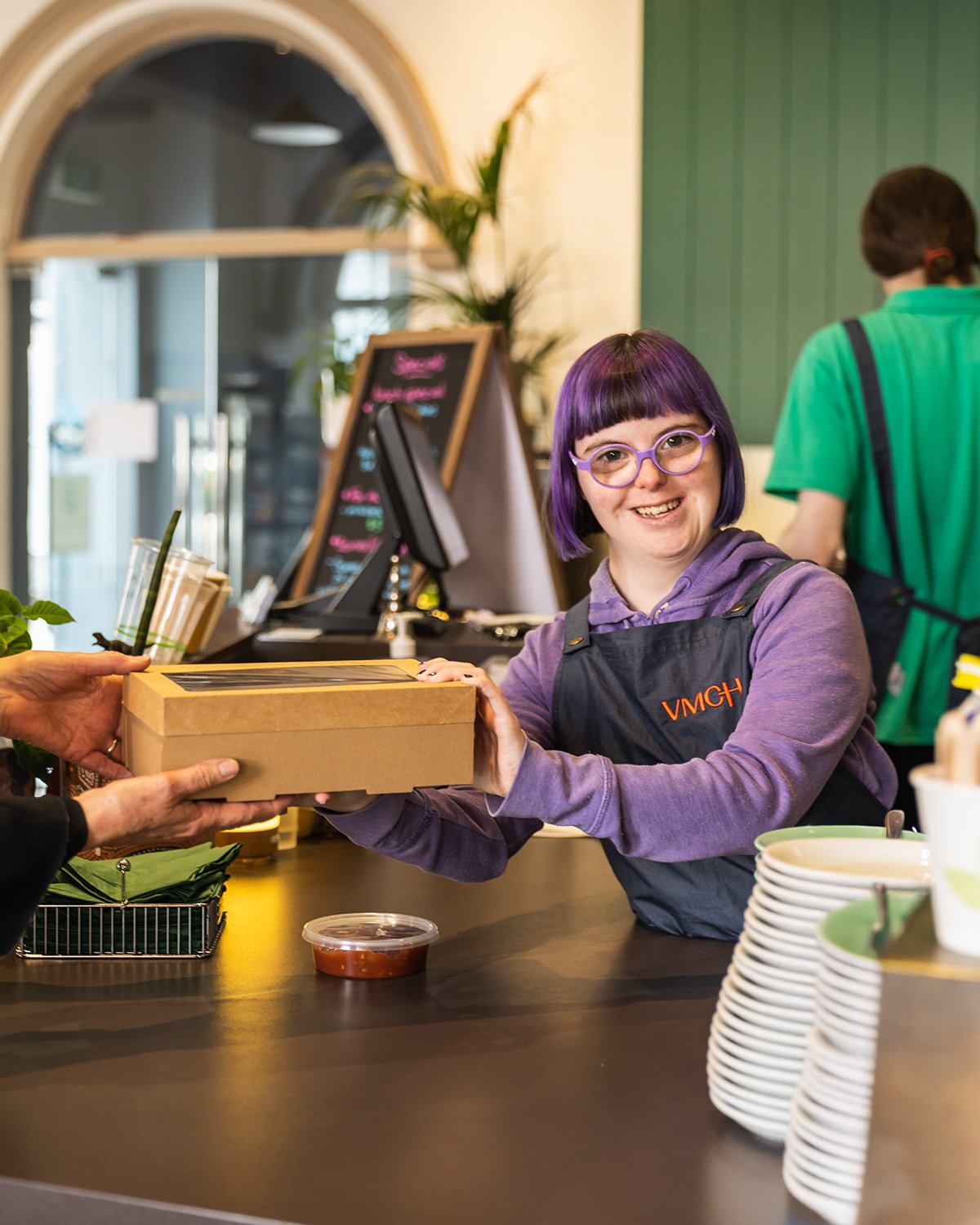 a woman standing behind a counter in a cafe