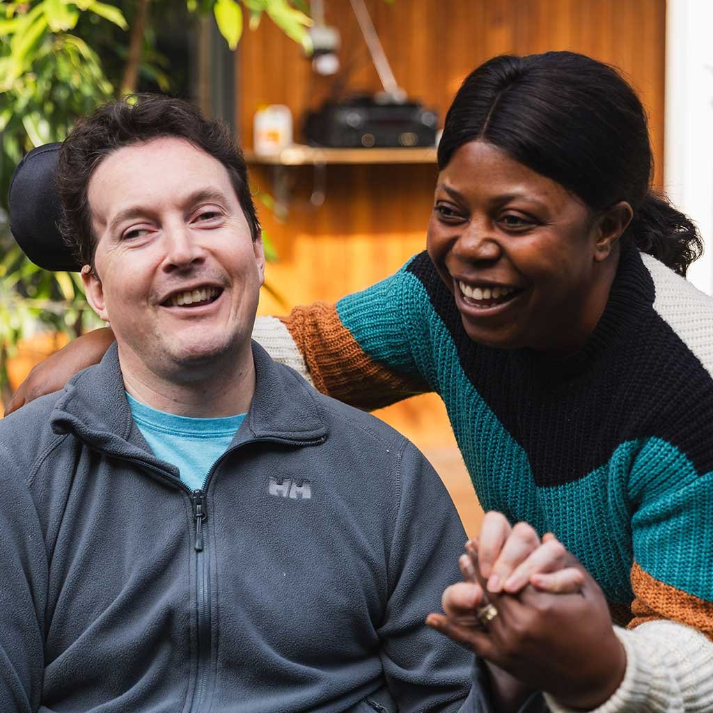 Two people sit in a yard 