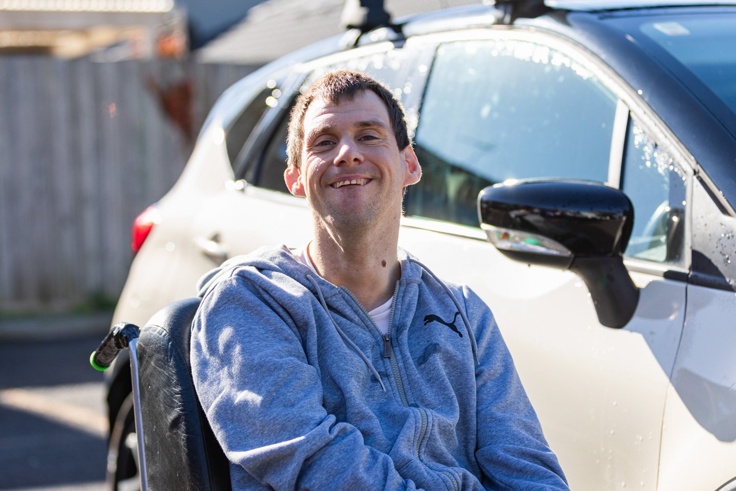 A person using a wheelchair smiles while spending time out in the community.