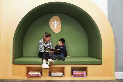 A young student and teacher reading a picture story book.
