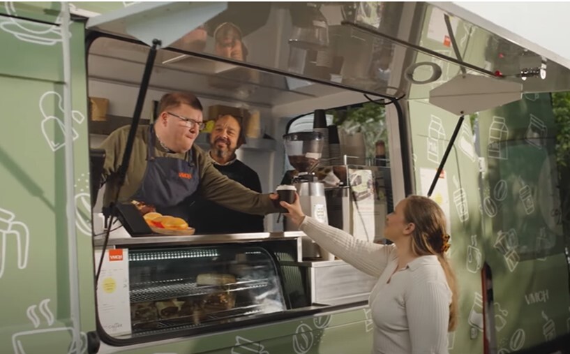 a man hands a coffee to a woman