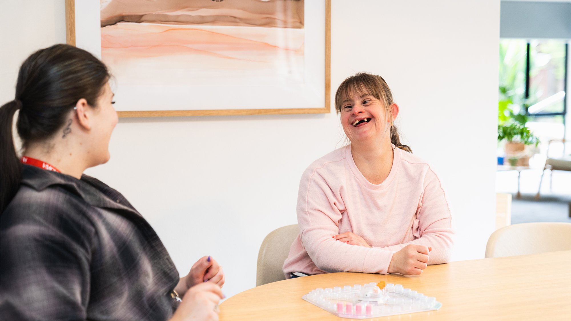 Two women play a board game inside a light and bright home