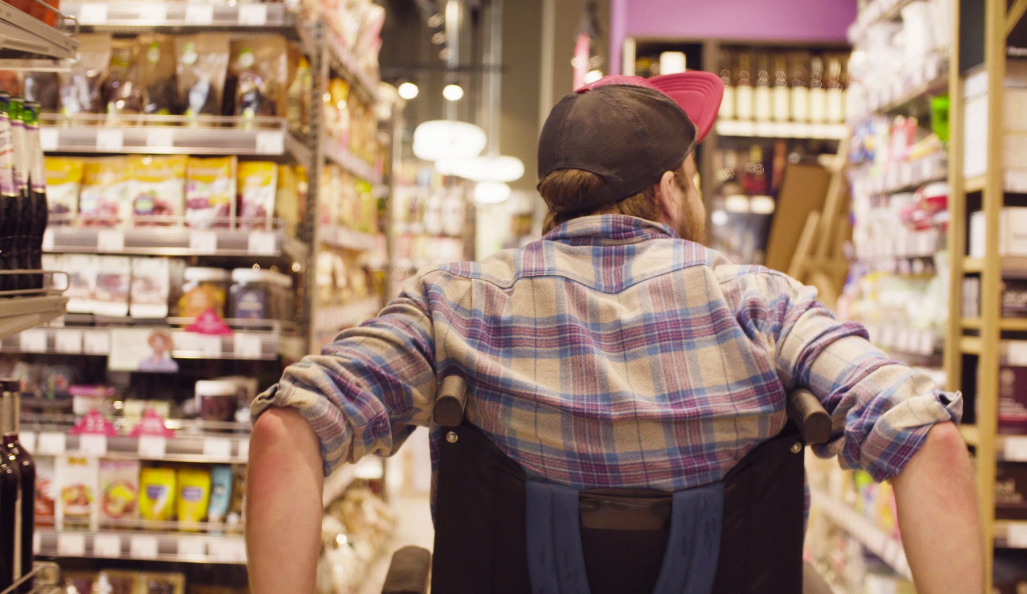 A person using a wheelchair shopping independently in a grocery store.