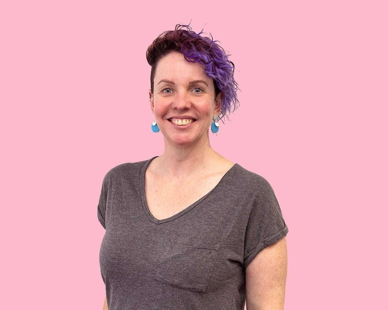 A woman stands in front of pink background