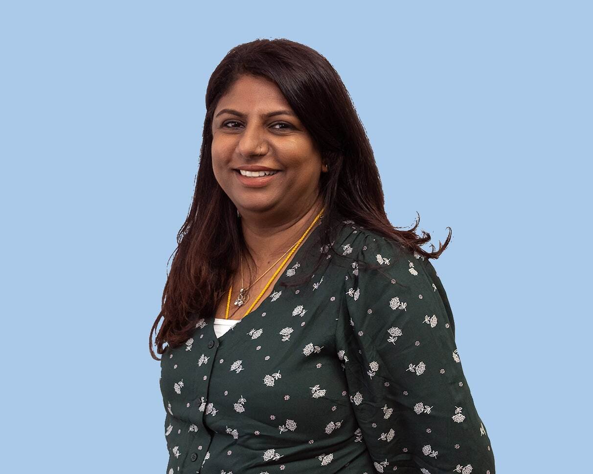 A woman in a print top smiles at camera