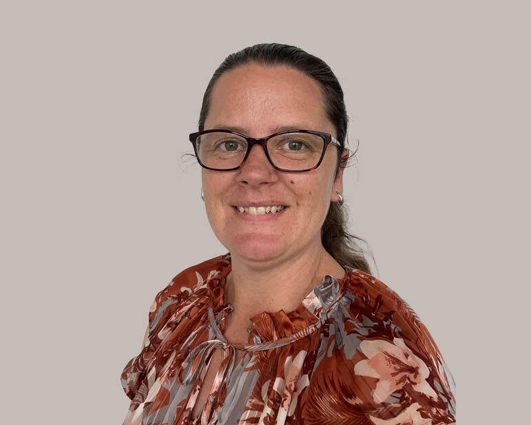 A woman wearing glasses smiles at camera