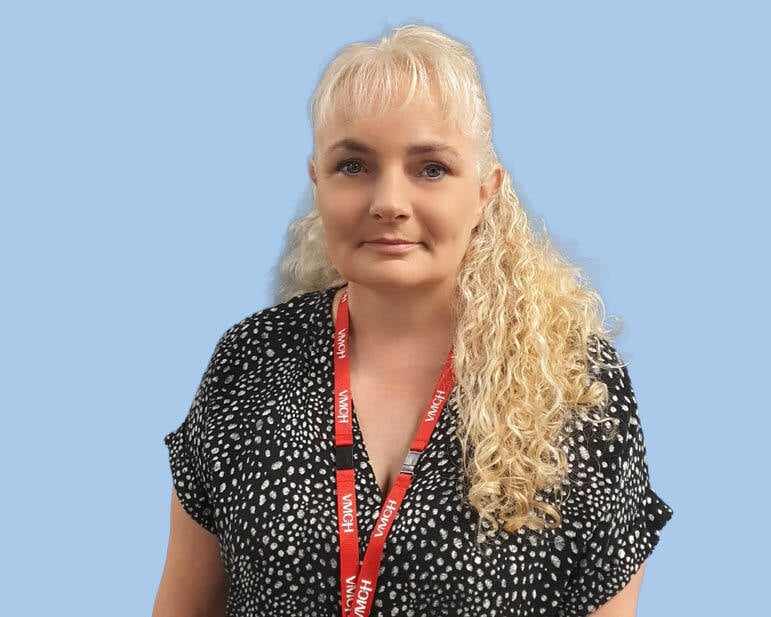 A woman with a blond ponytail looks at the camera